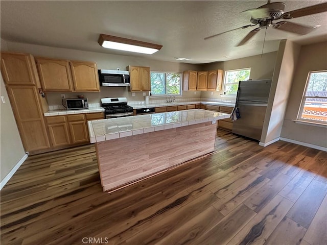 2240 Spring Valley Rd, Clearlake Oaks, CA 95423 - kitchen with appliances with stainless steel finishes, tile countertops, dark wood-style floors, ceiling fan, and a kitchen island