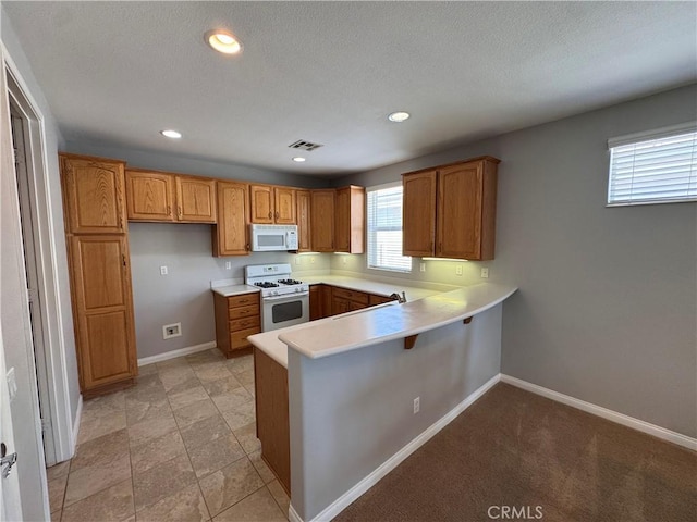 11115 Sun River Ct, Apple Valley, CA 92308 - kitchen with white appliances, a peninsula, brown cabinetry, light countertops, and recessed lighting