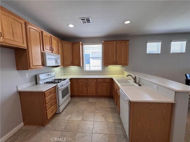 11115 Sun River Ct, Apple Valley, CA 92308 - kitchen with white appliances, a peninsula, light countertops, plenty of natural light, and recessed lighting