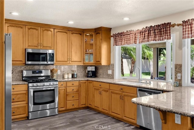 5829 Zapata Pl, Rancho Cucamonga, CA 91737 - kitchen with stainless steel appliances, light stone counters, glass insert cabinets, wood finished floors, and tasteful backsplash