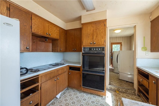 3142 Keith Ave, Castro Valley, CA 94546 - kitchen with freestanding refrigerator, light countertops, brown cabinetry, washer / clothes dryer, and stovetop with downdraft