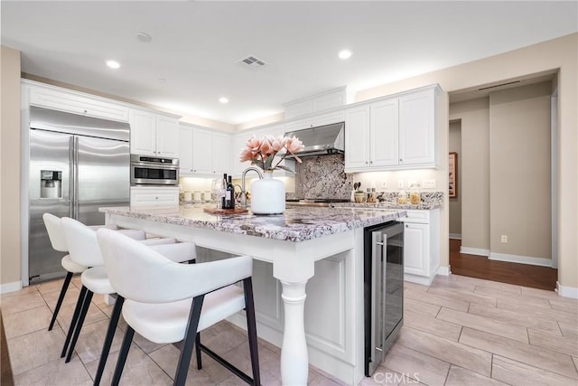 111 Spoke, Irvine, CA 92618 - kitchen with stainless steel built in fridge, beverage cooler, backsplash, wall chimney exhaust hood, and white cabinetry