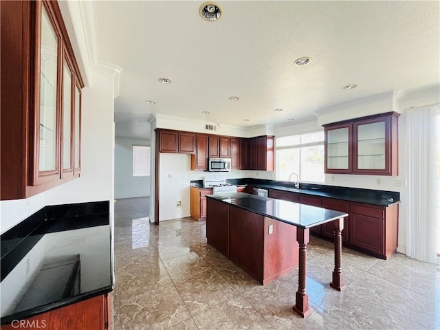 405 E Lurelane St, Rialto, CA 92376 - kitchen featuring stainless steel appliances, dark countertops, a center island, ornamental molding, and glass insert cabinets