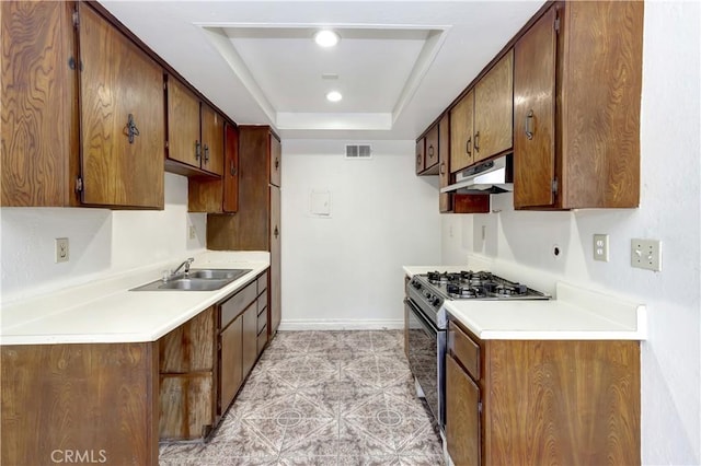 26441 Paseo Carmel Unit 8E, San Juan Capistrano, CA 92675 - kitchen with gas stove, under cabinet range hood, a raised ceiling, and light countertops