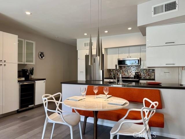 1655 E Palm Canyon Dr Unit 308, Palm Springs, CA 92264 - kitchen featuring beverage cooler, appliances with stainless steel finishes, wood finished floors, modern cabinets, and recessed lighting