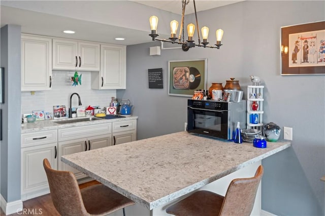 24055 W Paseo Del Lago Unit 962, Laguna Woods, CA 92637 - kitchen with a kitchen breakfast bar, tasteful backsplash, white cabinets, a chandelier, and decorative light fixtures