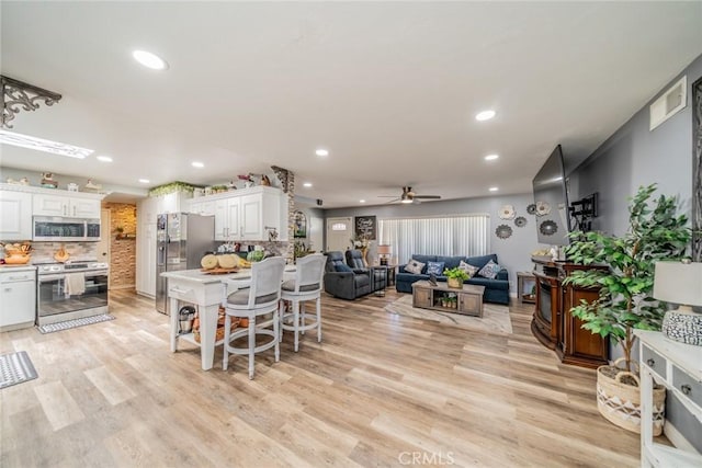 1181 W Westmont Ave, Hemet, CA 92543 - kitchen featuring appliances with stainless steel finishes, open floor plan, white cabinetry, a ceiling fan, and decorative backsplash