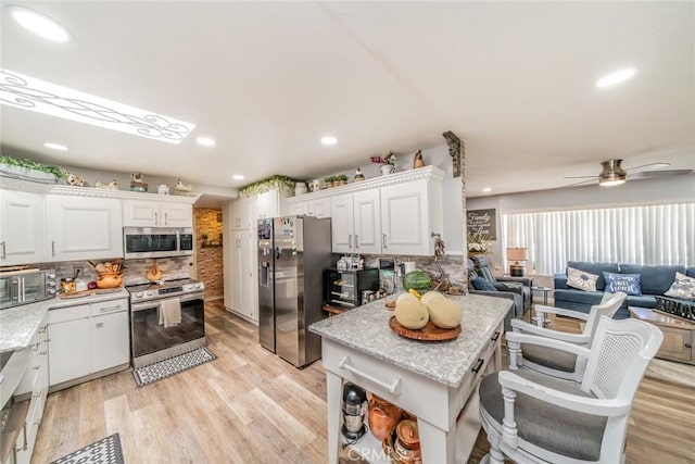 1181 W Westmont Ave, Hemet, CA 92543 - kitchen with stainless steel appliances, white cabinets, decorative backsplash, open floor plan, and recessed lighting