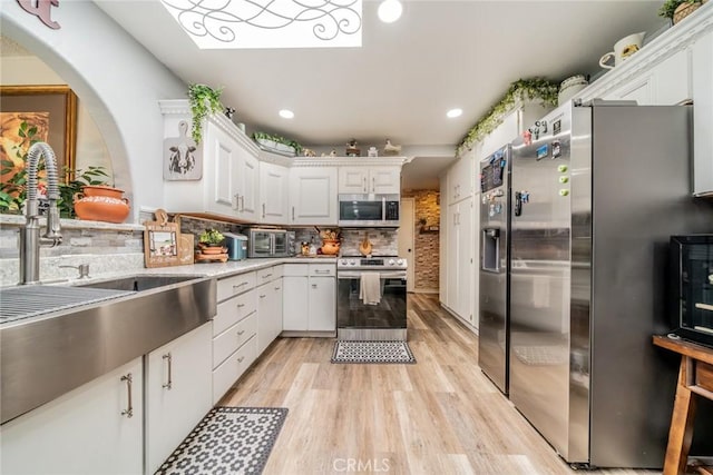 1181 W Westmont Ave, Hemet, CA 92543 - kitchen with stainless steel appliances, white cabinets, light wood-style flooring, decorative backsplash, and recessed lighting