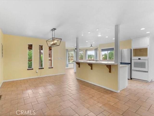 15540 China Rpds, Red Bluff, CA 96080 - kitchen featuring oven, freestanding refrigerator, a breakfast bar area, open floor plan, and light countertops