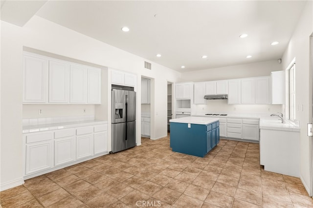 3959 Grandview Dr, Brea, CA 92823 - kitchen with stainless steel fridge, under cabinet range hood, blue cabinetry, white cabinets, and a kitchen island