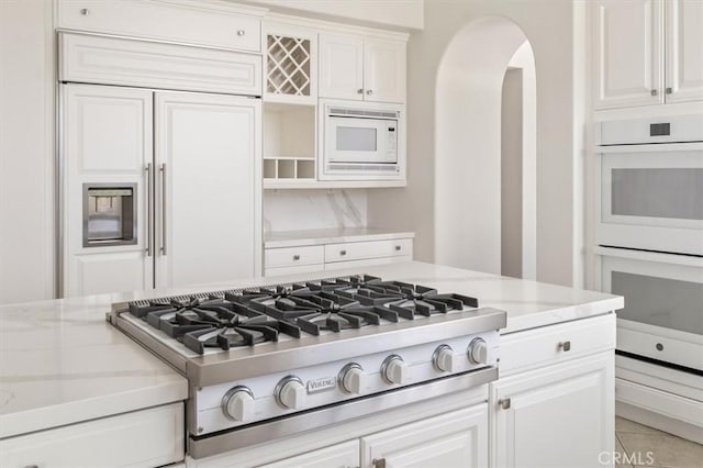 24711 Tiburon St, Valencia, CA 91355 - kitchen featuring built in appliances, white cabinets, arched walkways, light stone counters, and open shelves