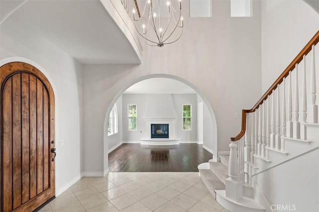 24711 Tiburon St, Valencia, CA 91355 - foyer with tile patterned flooring, arched walkways, a towering ceiling, a large fireplace, and stairway