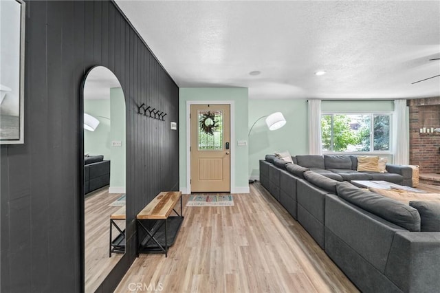 310 Teakwood Dr, Big Bear Lake, CA 92315 - living room featuring light wood-style flooring, a textured ceiling, arched walkways, an accent wall, and wood walls