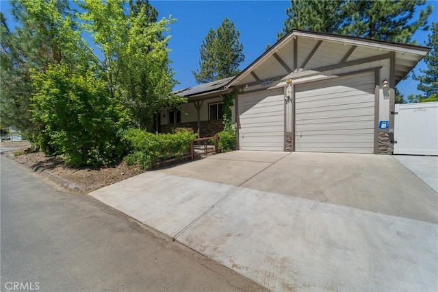 310 Teakwood Dr, Big Bear Lake, CA 92315 - view of front facade featuring an attached garage, roof mounted solar panels, driveway, and stone siding