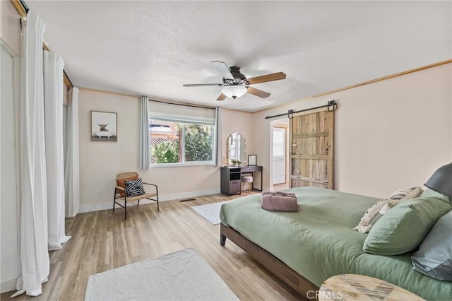 310 Teakwood Dr, Big Bear Lake, CA 92315 - bedroom with a barn door, light wood-type flooring, a ceiling fan, and a textured ceiling