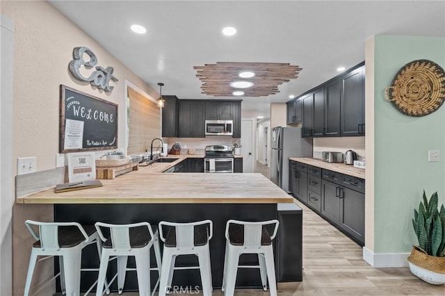 310 Teakwood Dr, Big Bear Lake, CA 92315 - kitchen with stainless steel appliances, butcher block countertops, a peninsula, a breakfast bar, and light wood finished floors