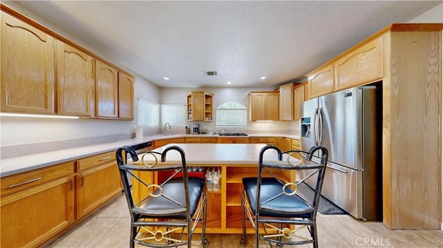12443 Bannock Dr, Apple Valley, CA 92308 - kitchen featuring stainless steel fridge with ice dispenser, open shelves, a kitchen breakfast bar, light countertops, and a kitchen island