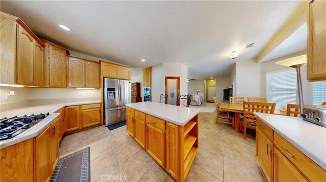 12443 Bannock Dr, Apple Valley, CA 92308 - kitchen featuring stainless steel fridge with ice dispenser, gas stovetop, a kitchen island, light countertops, and light tile patterned flooring