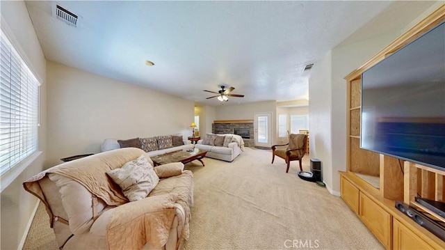 12443 Bannock Dr, Apple Valley, CA 92308 - living room featuring light carpet, ceiling fan, and a stone fireplace