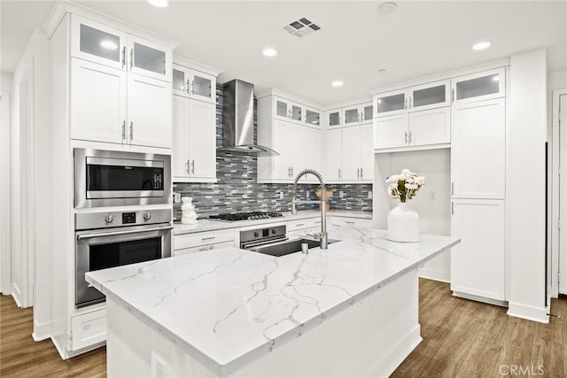 12260 Chorus Dr, Rancho Cucamonga, CA 91739 - kitchen with wall chimney range hood, stainless steel appliances, wood finished floors, white cabinetry, and tasteful backsplash