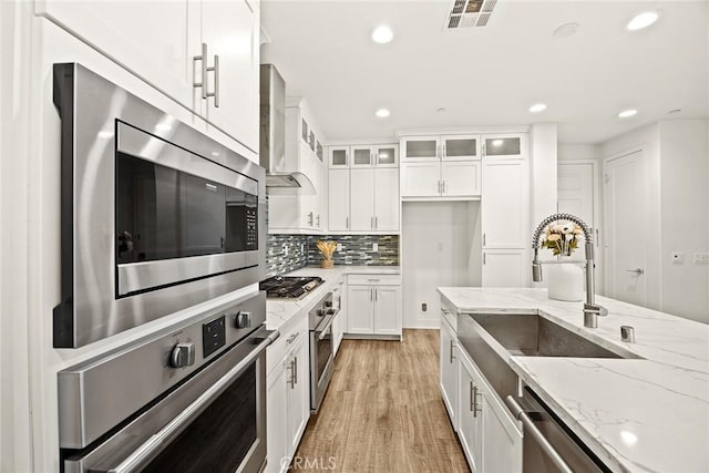 12260 Chorus Dr, Rancho Cucamonga, CA 91739 - kitchen with stainless steel appliances, wall chimney exhaust hood, white cabinets, light wood-type flooring, and recessed lighting