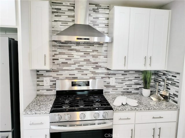900 S Ann St, Tulare, CA 93274 - kitchen featuring stainless steel range with gas cooktop, wall chimney range hood, freestanding refrigerator, and tasteful backsplash