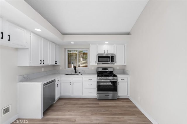36829 Burroughs Way, Palmdale, CA 93552 - kitchen with appliances with stainless steel finishes, white cabinets, recessed lighting, light wood finished floors, and light stone countertops