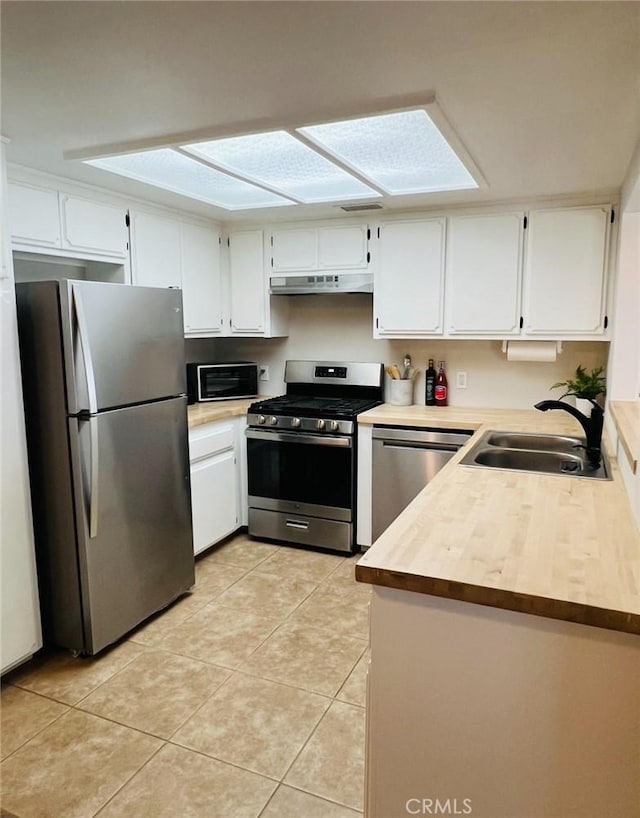 13330 Tamarisk Rd, Victorville, CA 92395 - kitchen with stainless steel appliances, under cabinet range hood, white cabinetry, and light countertops
