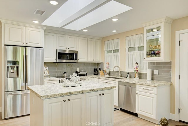 271 Avenida Sevilla Unit P, Laguna Woods, CA 92637 - kitchen with appliances with stainless steel finishes, decorative backsplash, glass insert cabinets, light stone countertops, and a kitchen island