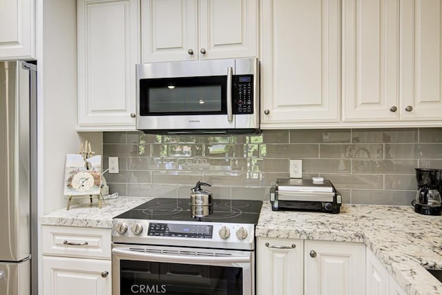 271 Avenida Sevilla Unit P, Laguna Woods, CA 92637 - kitchen with appliances with stainless steel finishes, white cabinetry, tasteful backsplash, and light stone counters
