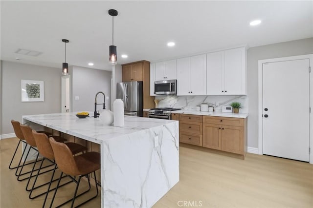 4203 Tolowa St, San Diego, CA 92117 - kitchen featuring appliances with stainless steel finishes, a breakfast bar, tasteful backsplash, light wood finished floors, and hanging light fixtures