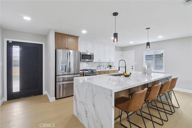 4203 Tolowa St, San Diego, CA 92117 - kitchen with appliances with stainless steel finishes, light wood finished floors, a center island with sink, recessed lighting, and light stone counters