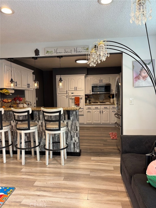 2835 Etiwanda Ave, Rialto, CA 92376 - kitchen featuring appliances with stainless steel finishes, a chandelier, a kitchen breakfast bar, a peninsula, and white cabinetry