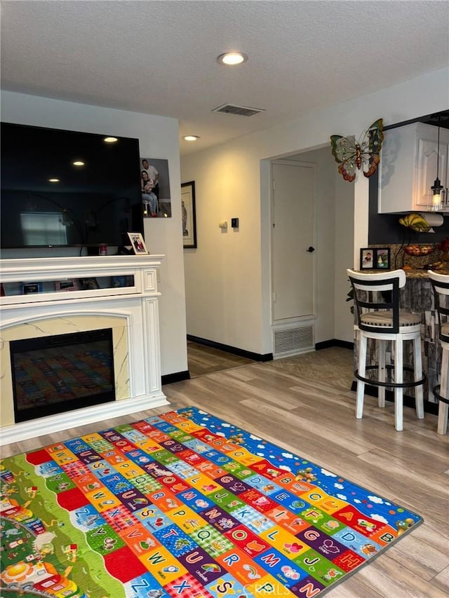 2835 Etiwanda Ave, Rialto, CA 92376 - living area featuring wood finished floors, recessed lighting, a glass covered fireplace, and a textured ceiling