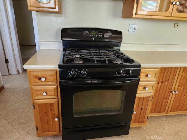 16708 Lawnwood St, La Puente, CA 91744 - kitchen featuring black gas range oven, light countertops, light tile patterned flooring, and brown cabinets