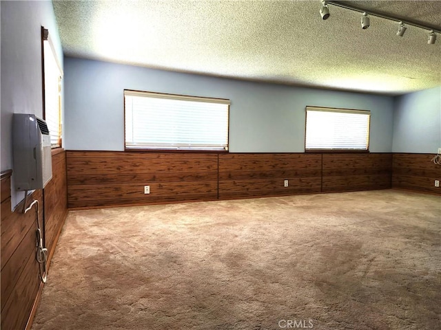 16708 Lawnwood St, La Puente, CA 91744 - spare room featuring wood walls, wainscoting, a textured ceiling, carpet, and rail lighting