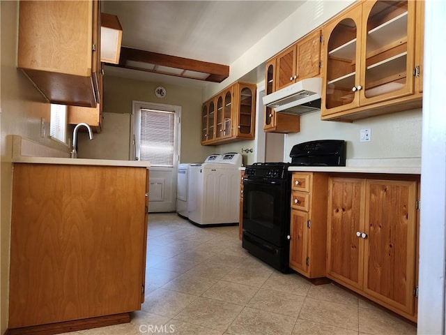 16708 Lawnwood St, La Puente, CA 91744 - kitchen featuring black gas range, under cabinet range hood, washing machine and clothes dryer, brown cabinetry, and light countertops