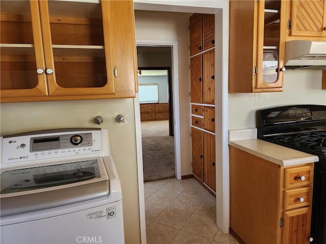 16708 Lawnwood St, La Puente, CA 91744 - kitchen with washer / dryer, gas stove, wall chimney range hood, light countertops, and glass insert cabinets