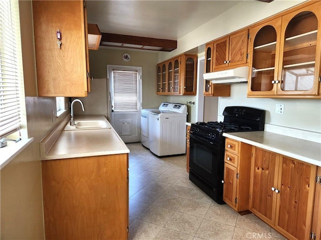 16708 Lawnwood St, La Puente, CA 91744 - kitchen with black gas stove, brown cabinetry, under cabinet range hood, washer and clothes dryer, and light tile patterned floors