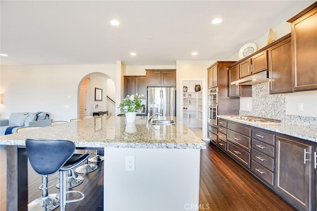 35212 Smith Ave, Beaumont, CA 92223 - kitchen featuring arched walkways, appliances with stainless steel finishes, a kitchen breakfast bar, an island with sink, and tasteful backsplash