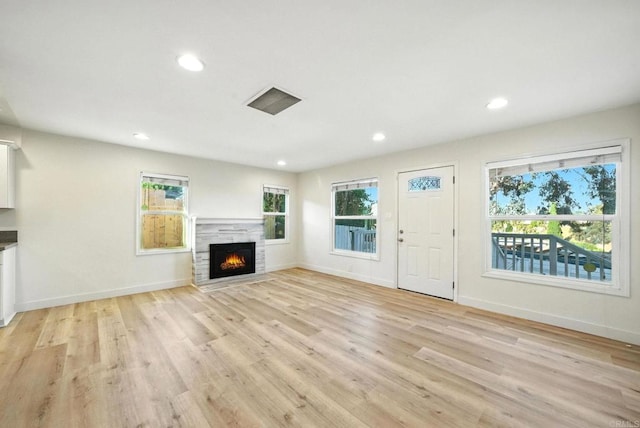 493133 Auburn, San Diego, CA 92105 - unfurnished living room featuring plenty of natural light, recessed lighting, a warm lit fireplace, and light wood finished floors