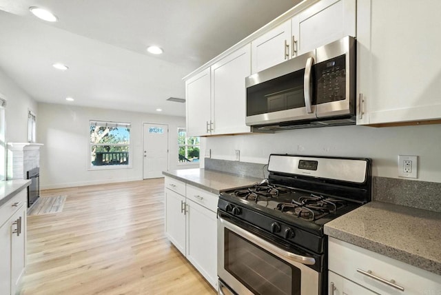 493133 Auburn, San Diego, CA 92105 - kitchen with appliances with stainless steel finishes, white cabinets, light wood-style flooring, recessed lighting, and light stone counters