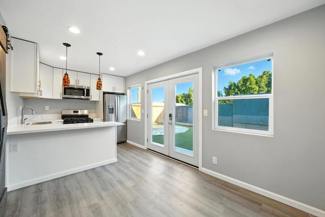493133 Auburn, San Diego, CA 92105 - kitchen featuring appliances with stainless steel finishes, light countertops, french doors, light wood finished floors, and a peninsula