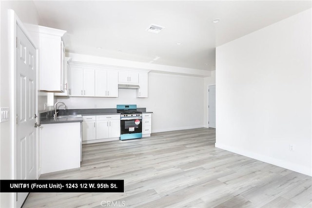 1241 W 95th St, Los Angeles, CA 90044 - kitchen featuring stainless steel range with gas stovetop, light wood-style floors, white cabinets, and dark countertops