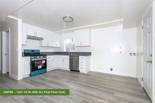 1241 W 95th St, Los Angeles, CA 90044 - kitchen with stainless steel appliances, under cabinet range hood, light wood finished floors, dark countertops, and white cabinets