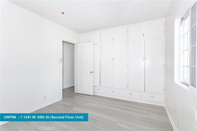 1241 W 95th St, Los Angeles, CA 90044 - unfurnished bedroom featuring multiple windows and light wood-style flooring