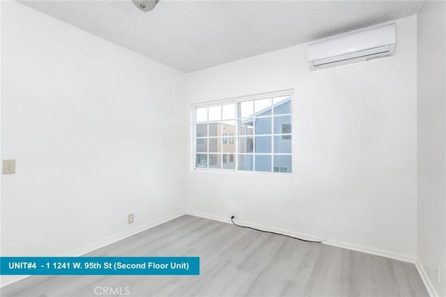 1241 W 95th St, Los Angeles, CA 90044 - empty room featuring wood finished floors, a wall unit AC, and a textured ceiling