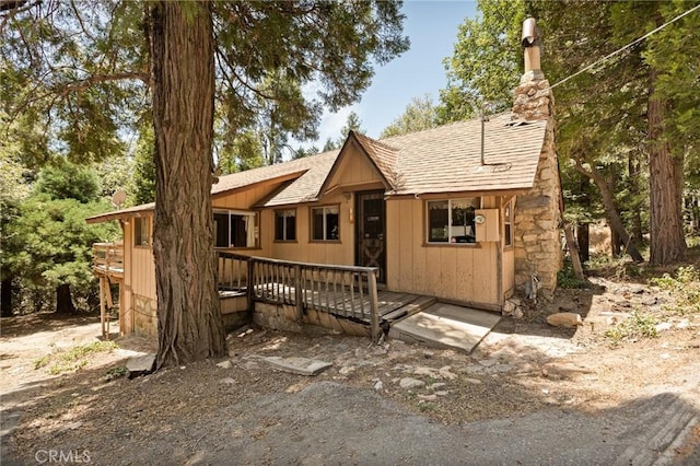 1230 Bear Springs Rd, Rimforest, CA 92378 - view of front facade with a shingled roof, a wooden deck, and a chimney