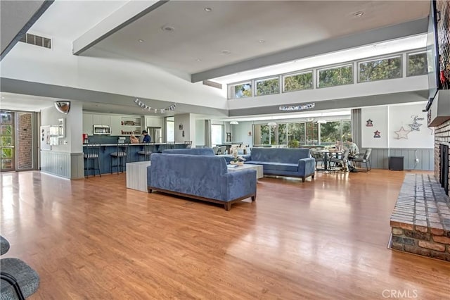 3603 W Hidden Ln Unit 210, Rolling Hills Estates, CA 90274 - living room with a brick fireplace, light wood-type flooring, wainscoting, and a high ceiling
